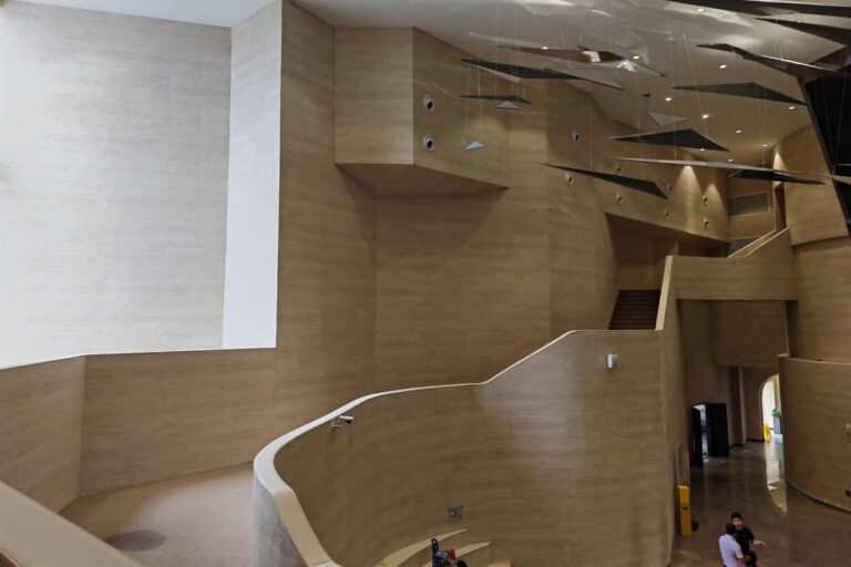 High-end hotel lobby design featuring bendable flexible stone veneer on curved columns, a trending peel and stick architecture solution for 2026.