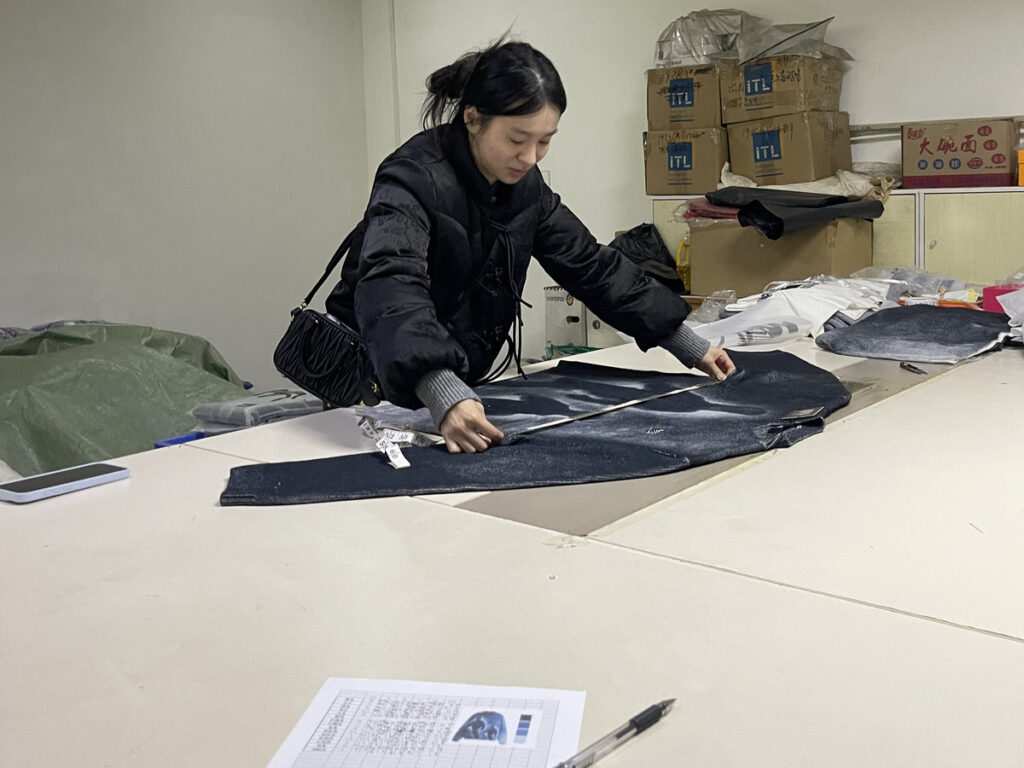 An apparel sourcing agent China inspecting garments from a streetwear clothing vendor before shipping